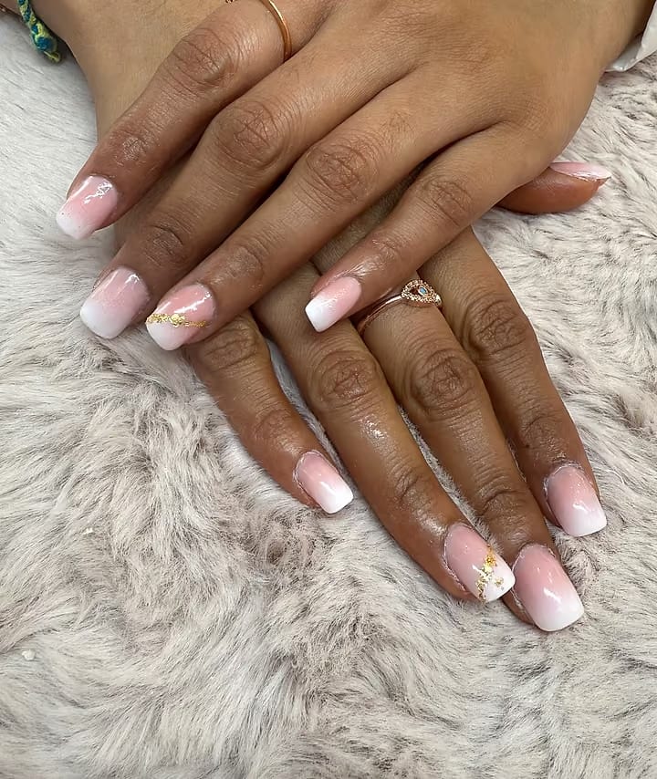 Pink-and-white French ombré nails with a touch of gold